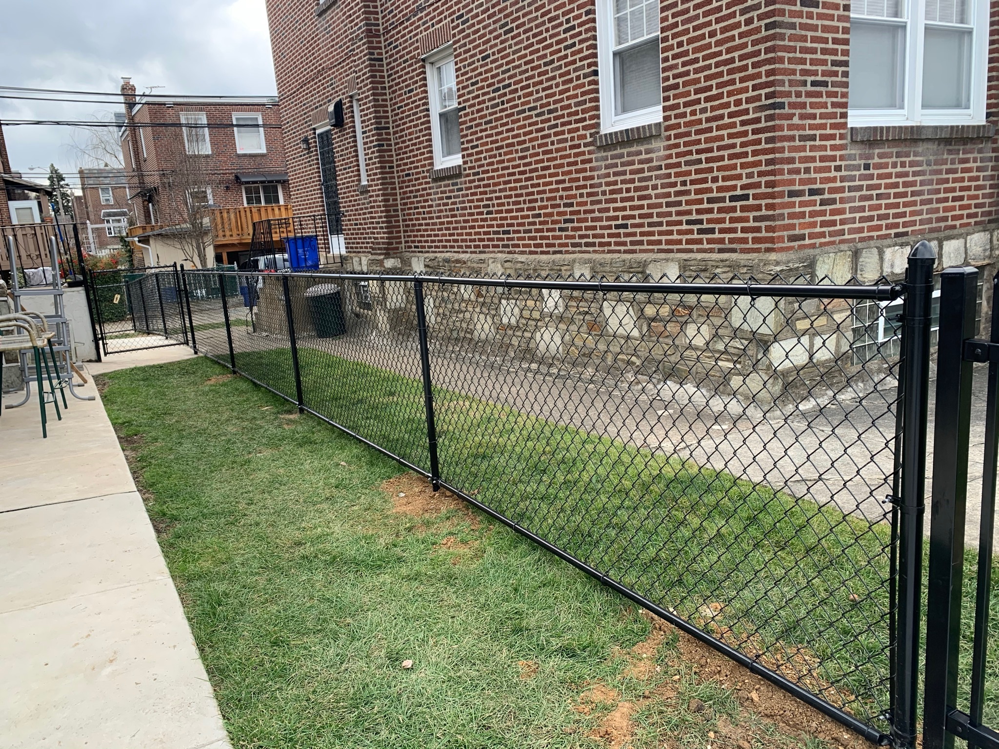 Black chain link fence with brick house